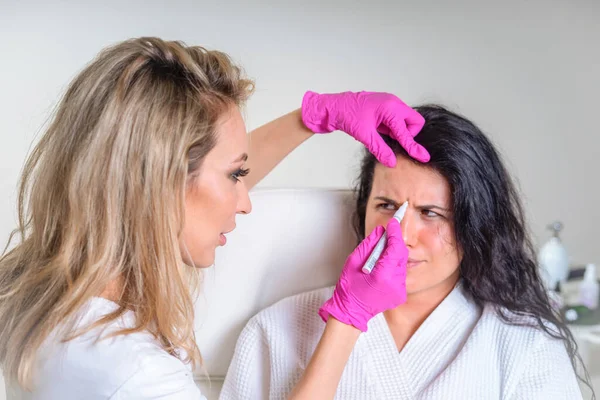 Kozmetológus használ arc marker a beteg arcát, mielőtt kozmetikai kezelés spa szalonban — Stock Fotó