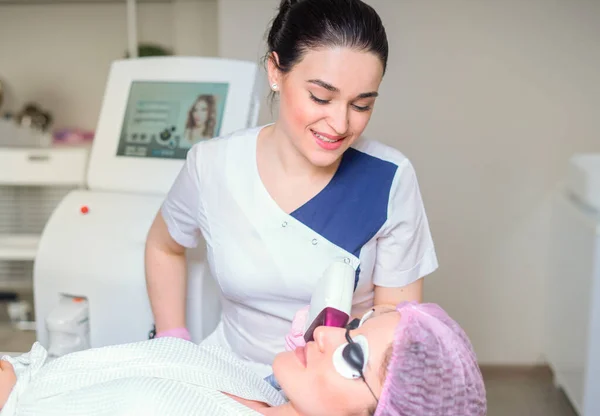 Lézeres kezelésben részesülő fiatal nő a kozmetikai klinikán. Védőszemüveggel borított szemek — Stock Fotó