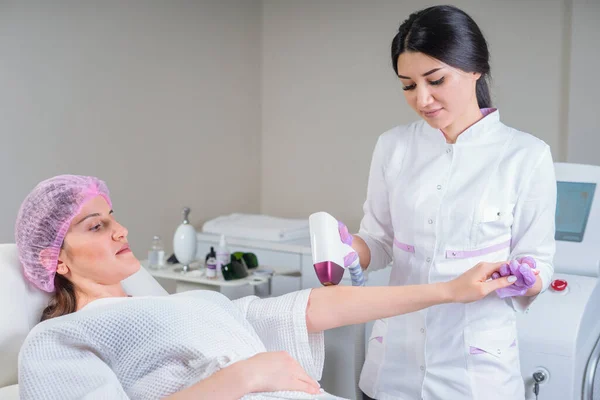 Beautician doing epilation on beautiful female hand in medical center. Female receiving laser hair removal — Stock Photo, Image