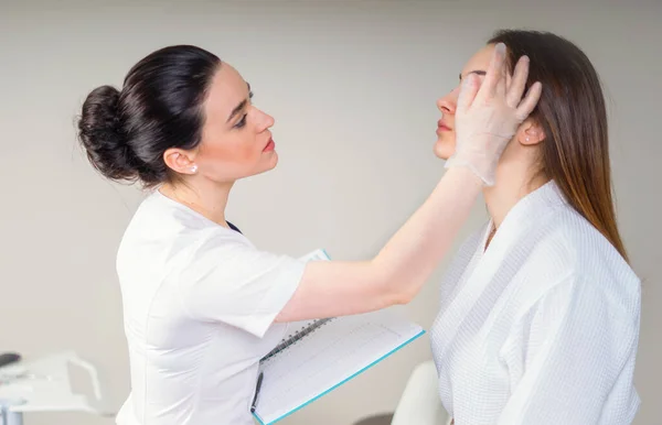 Cosmético profesional examinando la cutis de la muchacha en la clínica de la cosmetología estética — Foto de Stock