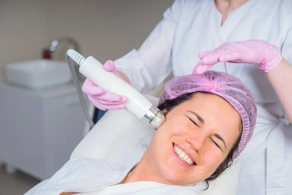 Jonge vrouw tijdens een gezichtsbehandeling met professioneel gereedschap in het medisch centrum — Stockfoto