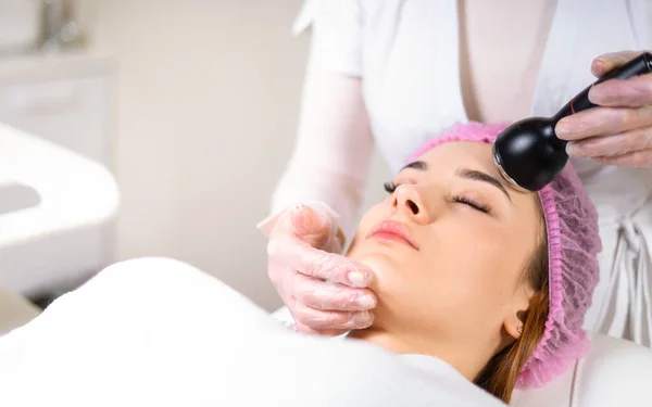 Young woman receiving treatment in cosmetology clinic. Cosmetology skin care. Aesthetic facial treatment Concept.