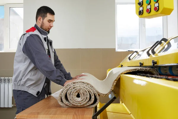 Man operating carpet automatic washing machine in professional laundry service