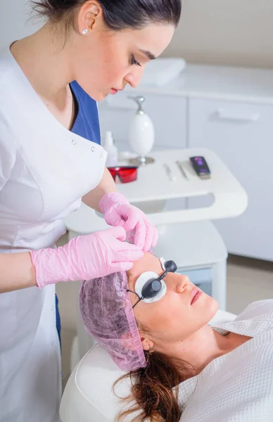 Jeune femme sous traitement laser en clinique de cosmétologie. Yeux couverts de lunettes de protection — Photo