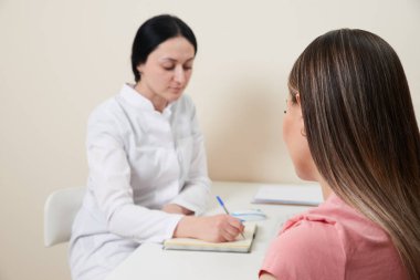 Hasta ofisinde bayan bir doktorla görüşüyor.