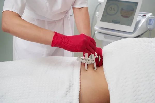 Cosmetoloog die Caliper gebruiken om lichaamsvet op taille lijn van patiënt te meten — Stockfoto