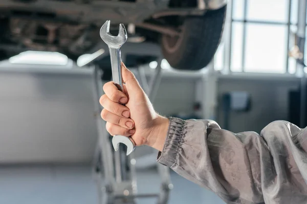 Autójavítás, karbantartás és a jármű ellenőrzési koncepció. Egy férfi csavarkulcsot tart egy autó előtt. — Stock Fotó