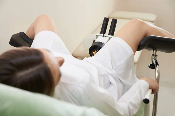 坐在妇科椅子上，带着显微镜的现代医学诊所病人 — 图库照片
