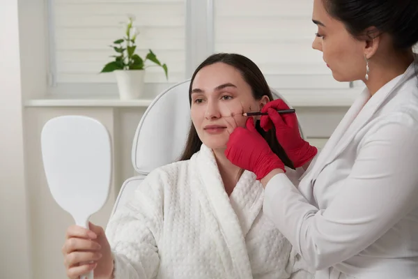 Cosmetologist χρησιμοποιώντας δείκτη προσώπου στο πρόσωπο του ασθενούς πριν από τη θεραπεία ομορφιάς στο σαλόνι σπα — Φωτογραφία Αρχείου