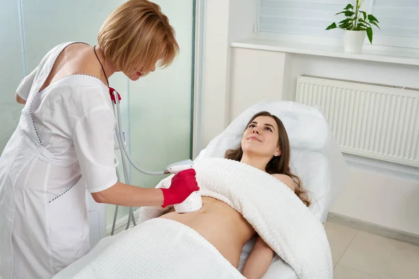 Profesjonalny kosmetolog wykonujący zabieg podnoszenia częstotliwości radiowych na brzuchu kobiety — Zdjęcie stockowe
