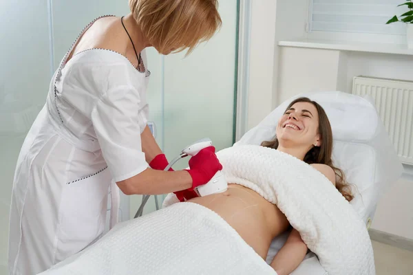 Profesjonalny kosmetolog wykonujący zabieg podnoszenia częstotliwości radiowych na brzuchu kobiety — Zdjęcie stockowe