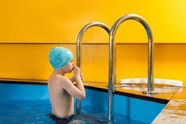 Хлопчик плаває в критому басейні, розважаючись під час занять плаванням — стокове фото