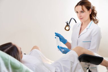 Jinekolog, cinsel yolla bulaşan hastalıkları test etmek için vajinal bez kullanıyor.