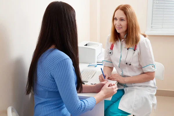 Ärztin im Gespräch mit junger Patientin am Schreibtisch im Büro — Stockfoto