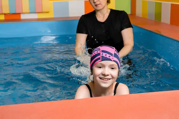 Trener uczy dziecko w krytym basenie jak pływać i nurkować — Zdjęcie stockowe