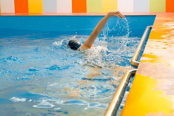 Хлопчик плаває в критому басейні, розважаючись під час занять плаванням — стокове фото