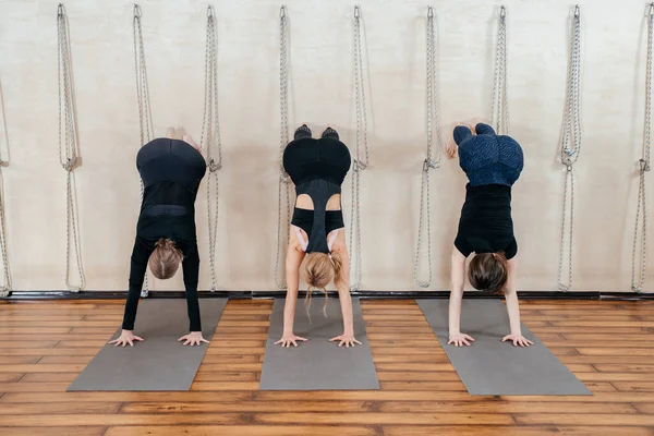 Kvinnor lär sig att stå på händerna nära väggen i studion. Upp och ner yoga position — Stockfoto