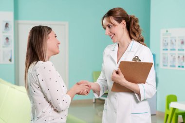 Dosyası olan bir doktor ve modern kliniğin koridorunda duran genç bir bayan hasta.