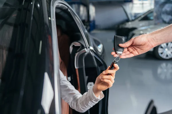 Automobilový dealer dává klíč k novému autu mladé ženě — Stock fotografie