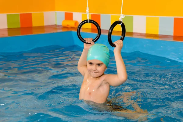 Kind in het zwembad excersizing met sport ringen — Stockfoto