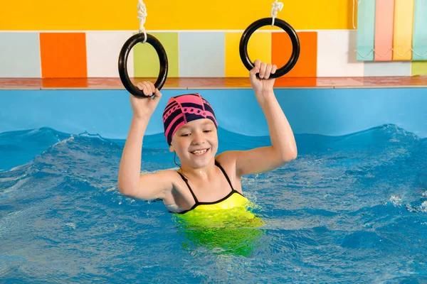 Child in swimming pool excersizing with sport rings — Stock Photo, Image