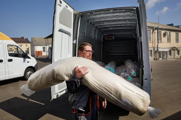 Arbetaren står nära lastbilen full av mattor. Begreppet städning — Stockfoto