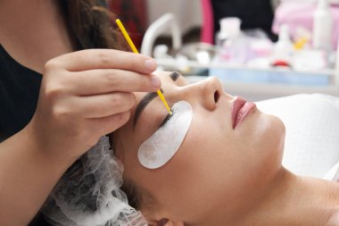 Kirpik uzatma prosedürünü kapat. Güzellik salonunda uzun kirpikleri olan güzel bir kadın