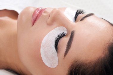 Güzellik salonunda uzun kirpikleri olan güzel bir kadın. Kirpik uzatma işlemi