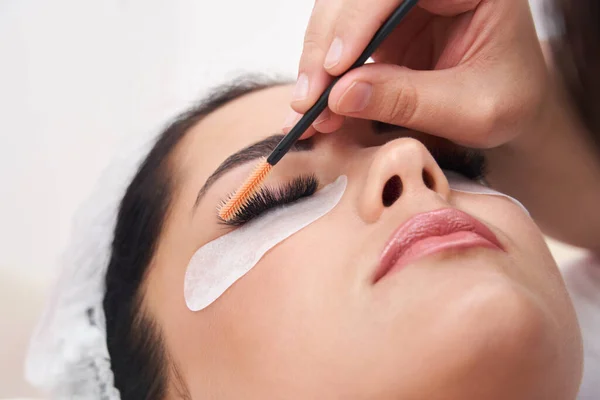 Cosmetologo facendo l'estensione e la correzione delle ciglia con pennello — Foto Stock