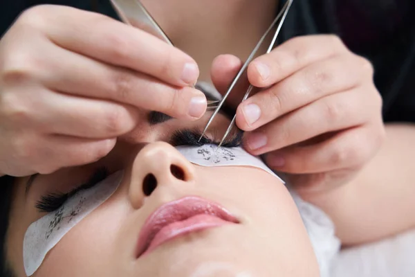 Eyelash extension procedure with tweezers in beauty salon — Stock Photo, Image