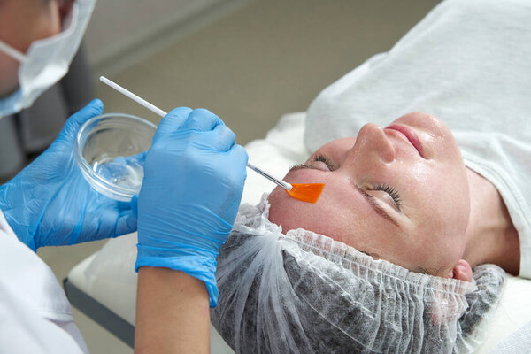 cosmetologist applies oil to the client face in the beauty salon