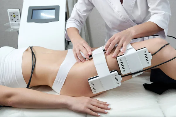 Hermosa mujer recibiendo terapia de electroestimulación. Equipo de liposucción láser. La grasa cosmética reduce el tratamiento. Procedimiento contra la celulitis — Foto de Stock