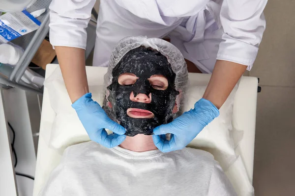 Mujer joven con una máscara de burbuja de oxígeno negro en su cara en el salón de belleza — Foto de Stock