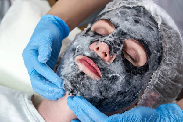 Jovem com uma máscara de bolha de oxigênio preto em seu rosto no salão de beleza — Fotografia de Stock