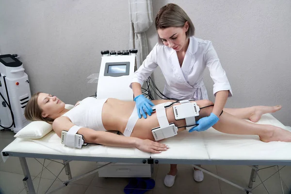 Hermosa mujer recibiendo terapia de electroestimulación. Equipo de liposucción láser. La grasa cosmética reduce el tratamiento. Procedimiento contra la celulitis — Foto de Stock