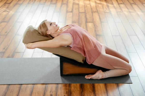 Mulher madura fazendo exercícios de alongamento no banco de backbend de ioga no estúdio — Fotografia de Stock