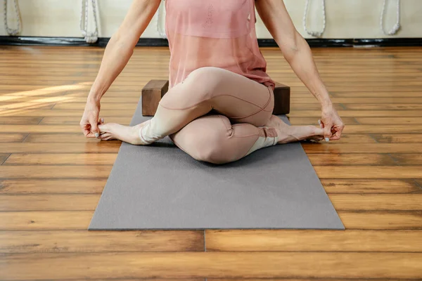 Mogen stark kvinna som gör yoga eller pilates stretching avslappning motion i vit loft studio interiör. Andning, koncentration, hälsosam livsstil koncept — Stockfoto
