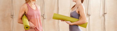 Spor salonunda yoga minderini tutan iki kadının spor kıyafetleri içinde spor salonuna ya da yoga eğitimine başlamaya hazır olduklarını gördüm. Spor yaşam tarzı kavramı. Yoga konsepti