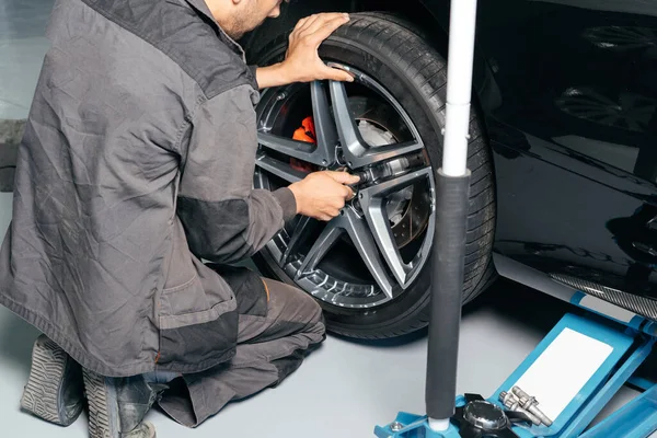 Szerelő javítás autó kerék autószerelő műhely segítségével lift jack és elektromos fúró, hogy lazítsa el a csavarokat. a szerviz- vagy gumiabroncs-csere fogalma. — Stock Fotó