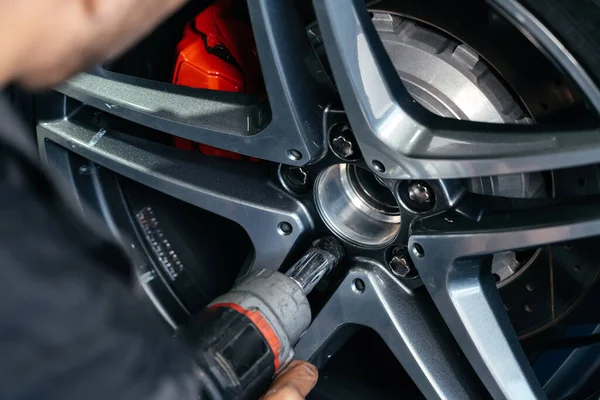 Mudando a roda do carro na oficina de reparação de automóveis usando uma broca elétrica para soltar os parafusos .concept de serviço ou substituição. — Fotografia de Stock