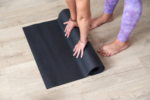 Mulher rolando ioga preto ou tapete de fitness depois de trabalhar em casa na sala de estar. Vida saudável, conceitos de ioga — Fotografia de Stock