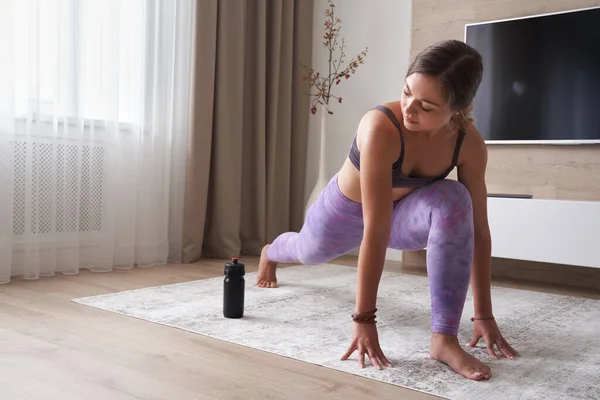 Jonge sportieve vrouw die thuis yoga beoefent in de woonkamer. Sport en fitness concept — Stockfoto