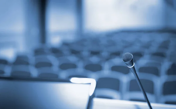 Rostrum con micrófono y ordenador en la sala de conferencias, tonos azules — Foto de Stock
