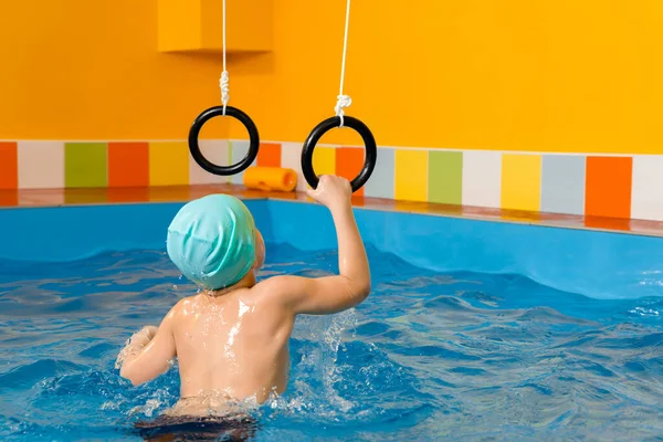 Дитина в басейні збуджує спортивні кільця — стокове фото