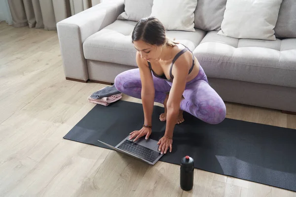 Mooie atletische sportieve vrouw zitten op yoga mat na sommige oefeningen dranken eiwit schudden of water — Stockfoto