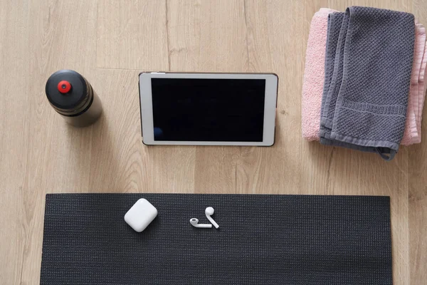 Visão superior de tablet, fones de ouvido, tapete de ioga e toalhas antes do treino. Conceito de ioga ou fitness — Fotografia de Stock