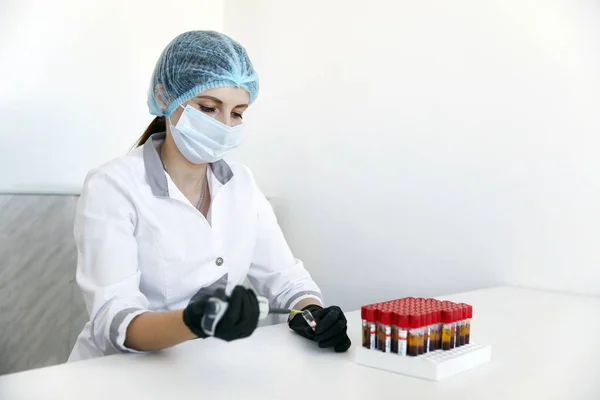 Laboratorietekniker med slang av blodprov och rack med andra prover. laboratorietekniker som håller blodrörsprov för undersökning — Stockfoto