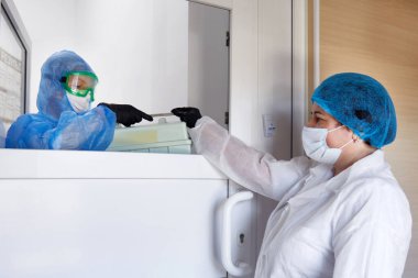 Bilim adamı, içinde kan örnekleri olan konteynırı laboratuardaki bir hemşireye veriyor. Tıbbi numune taşımak için soğutma kutusu. Tıbbi araştırma konsepti