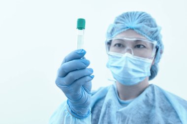 Laboratuvarda araştırma ve analiz yapan iki test tüpü tutan kadın bilim adamı. Sağlık ve tıp konsepti. Mavi tonlu