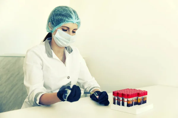 Laboratorietekniker med slang av blodprov och rack med andra prover. laboratorietekniker som håller blodrörsprov för undersökning. sepiatoner — Stockfoto